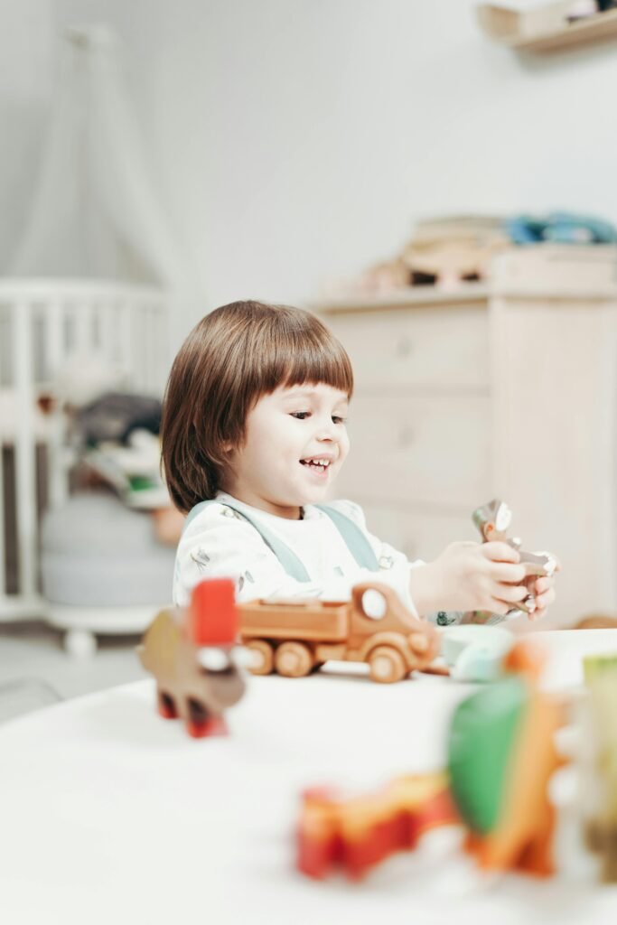 Happy child enjoys playing with colorful wooden toys in a bright indoor setting.