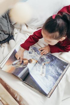 Young girl exploring a space-themed book indoors, capturing curiosity and enjoyment.